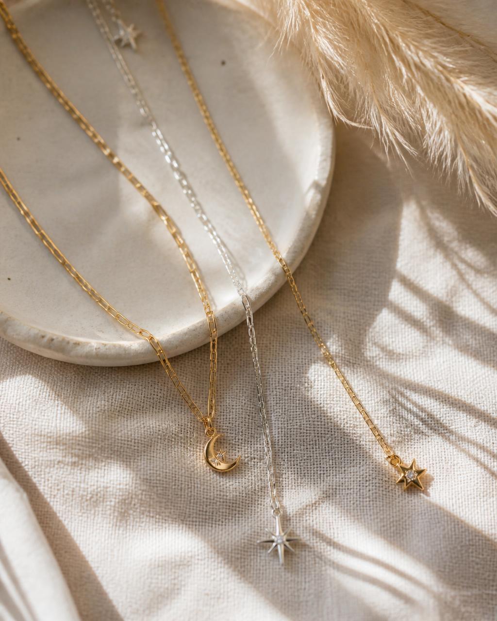 Fine gold and silver chains with celestial charms on natural linen